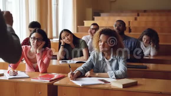 厌倦和无聊的学生正在听老师讲课在笔记本上做笔记坐在大学的课桌上视频的预览图