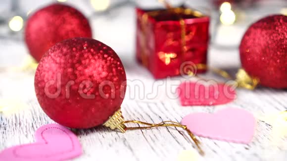 白色木桌上的圣诞树装饰品红色的球和礼品盒粉红色的心圣诞树亮灯亮灯视频的预览图