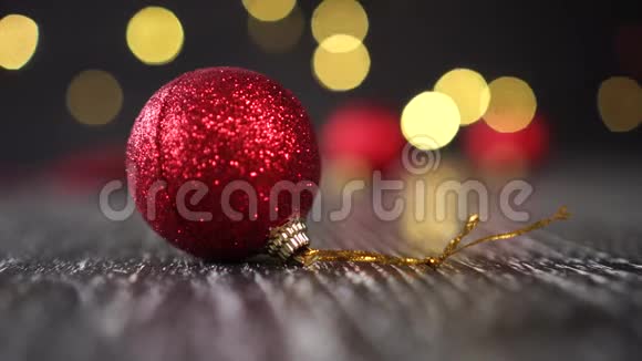 红色圣诞球金色的绳子在一个黑暗的木桌特写圣诞花环在黑色背景上闪烁视频的预览图