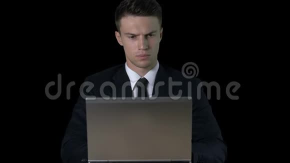 敏锐的商人在黑色背景下的笔记本电脑上工作哑光效果视频的预览图