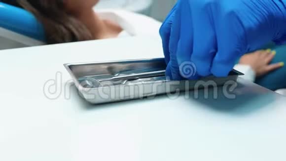 戴着蓝色手套的牙医拿着仪器开始用牙镜牙坝治疗病人的牙齿视频的预览图