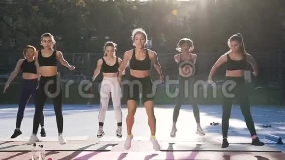 女子健身课在户外运动中做跳跃运动的正面景观视频的预览图