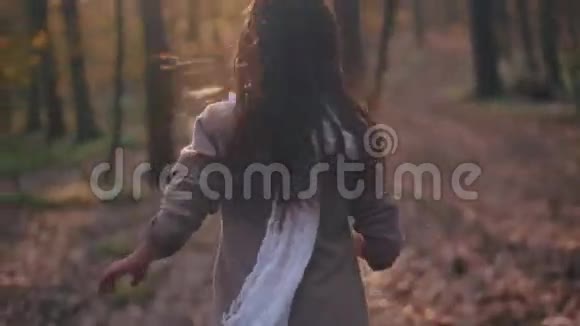 深色头发的小女孩带着鲜艳的围巾和长发惊恐的孩子正匆忙地穿过神秘的森林视频的预览图
