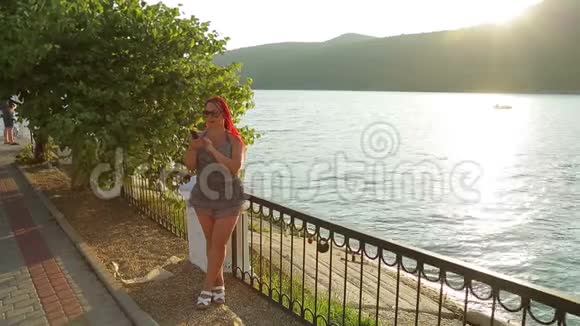在一个山湖的背景下一个晒黑的年轻女人在长廊上的信使中交流视频的预览图