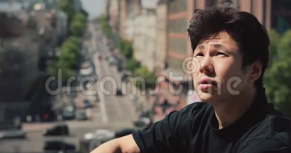 亚洲男人坐在城市里放松户外视频的预览图