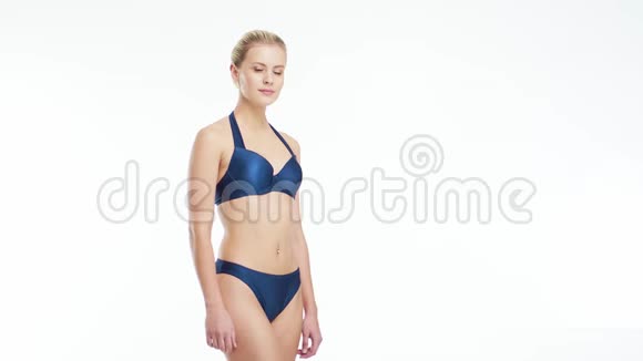 年轻美丽健康和自然的金发女人穿蓝色泳衣摆在孤立的白色背景体育健身视频的预览图