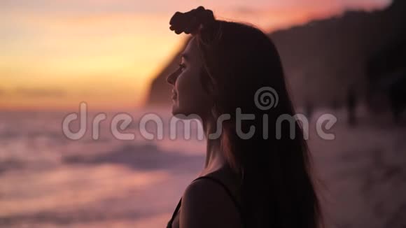 海面上的日落年轻女子站在海滩上举手4k视频的预览图