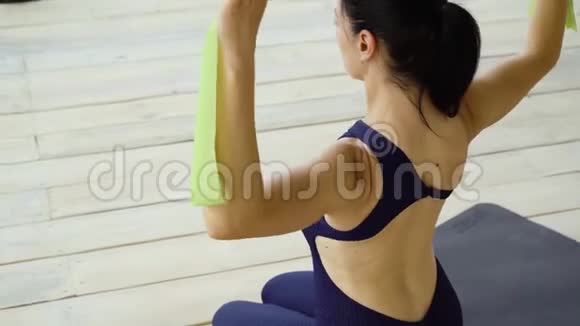 运动女孩在工作室里用橡皮筋伸展背部视频的预览图