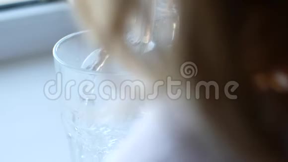 一个孩子把水壶里的水倒进玻璃杯里视频的预览图