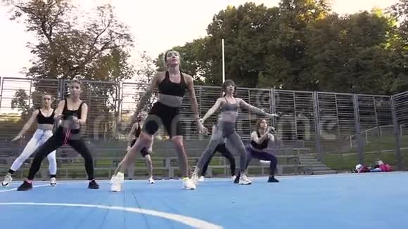 一群年轻的运动型漂亮的女士在户外做深蹲运动视频的预览图