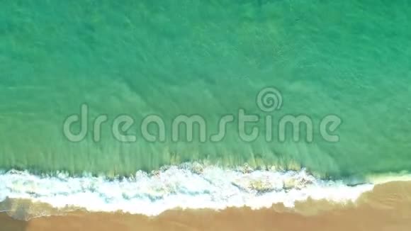 从绿色海水表面的无人机照相机俯视海浪拍打在沙质海岸视频的预览图