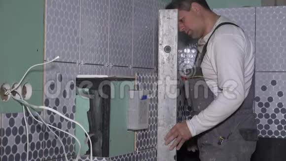 工人检查瓷砖铺设在WC壁橱框架上的水平视频的预览图