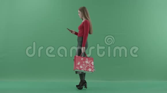 穿着休闲服的漂亮女人拿着购物袋在手机上说话她站在左边视频的预览图