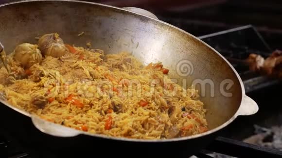 在大锅里煮熟的诱人的皮拉夫传统的亚洲菜米饭羊肉和蔬菜在烤架上煮熟视频的预览图