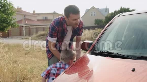 善良的白种人爸爸耐心地教他的儿子如何引擎盖慢动作洗车视频的预览图