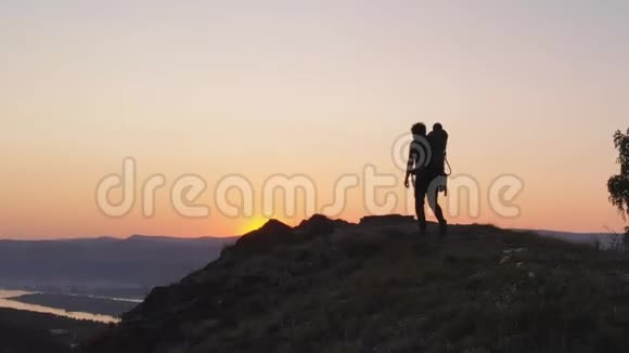 日落时分父亲和他的小婴儿在山上小径上徒步旅行的剪影视频的预览图