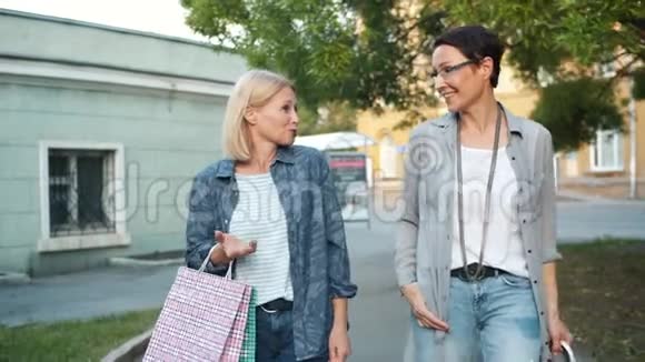 女士带着购物袋在户外散步的慢动作说笑视频的预览图