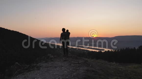 一个男人向他的孩子展示夕阳沿着一条山路走视频的预览图