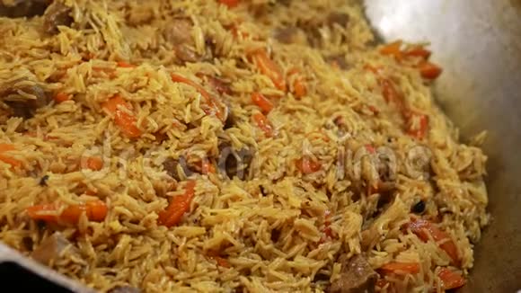 在大锅里煮熟的诱人的皮拉夫传统的亚洲菜米饭羊肉和蔬菜在烤架上煮熟关门视频的预览图