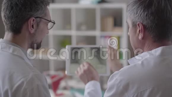 两位经验丰富的男医生在药片上检查肺部x光讨论医学健康概念视频的预览图