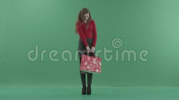 漂亮的困惑的女人穿着休闲服摆着购物袋她站在一间工作室里反对视频的预览图