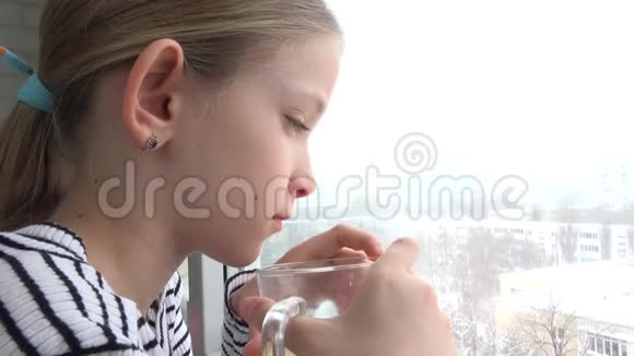 生病的孩子望着窗外悲伤的孩子脸在喝茶暴风雪的冬天视频的预览图