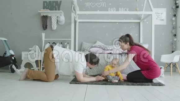 快乐的父母和婴儿一起在室内爬行视频的预览图