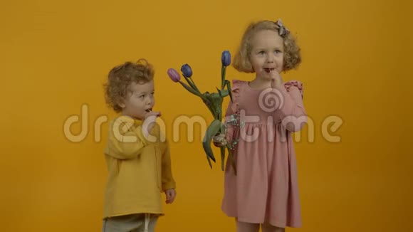 带着郁金香在黄色背景下吃糖果的孩子笑视频的预览图