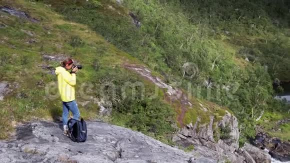 一位女士用数码单反相机从山上拍摄挪威风景视频的预览图