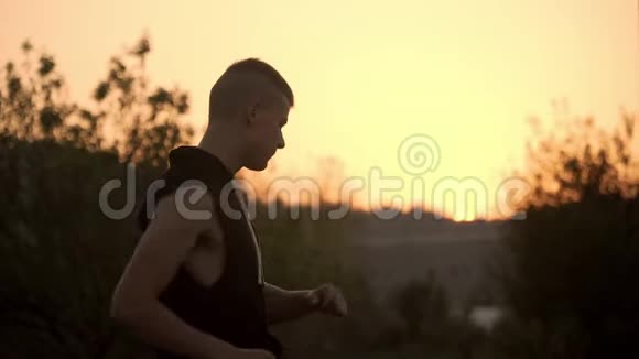在大自然的日落时分在户外进行剧烈运动之前一个男人热身运动的决心视频的预览图