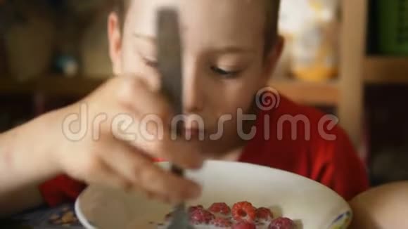 小男孩用牛奶勺慢吞吞地吃新鲜的覆盆子视频的预览图