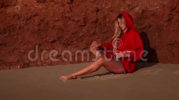 小女孩坐在海边泥山附近潮湿的沙滩上做瑜伽姿势视频的预览图