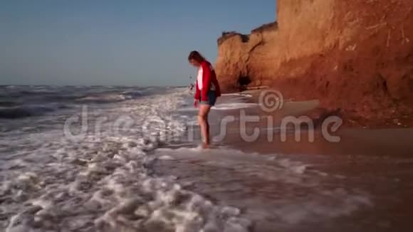 海滩上的小女孩走近海边的粘土山视频的预览图