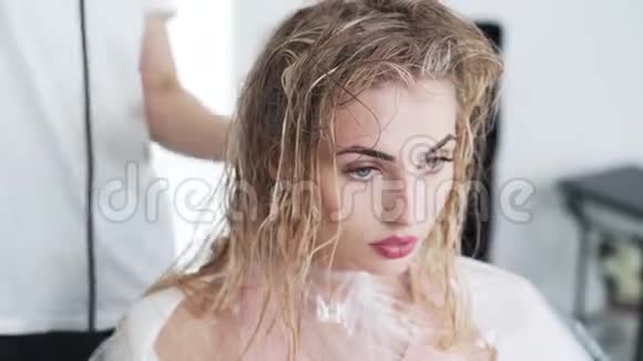 理发师用吹风机吹干女性头发同时用空气触摸技术染色视频的预览图
