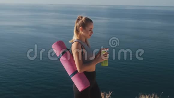 运动服的女士在海边运动后从瓶子里喝水视频的预览图
