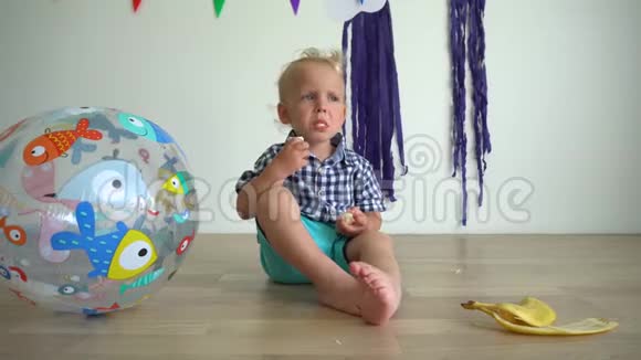 有魅力的男孩2岁吃香蕉孩子坐在地板上万向节运动视频的预览图