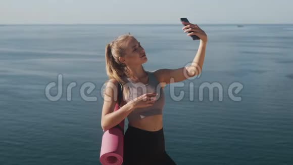 运动服中的女孩在训练结束后在手机上自拍表示和平的姿态视频的预览图