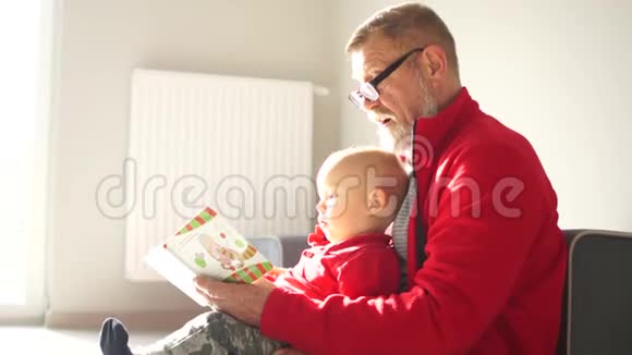 老人和一个18个月的男孩正坐在地板上读一本儿童书祖父和孙子视频的预览图