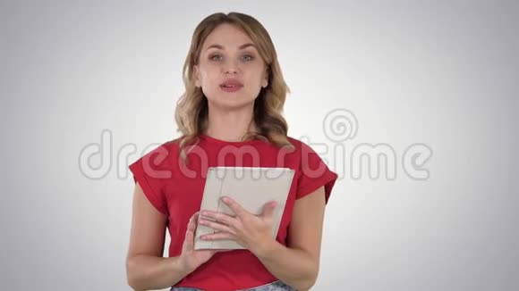金发女人穿着红色的平板电脑在渐变背景下阅读到相机上视频的预览图