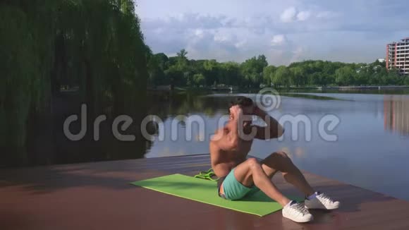 活跃的壮汉在木湖码头做腹肌练习视频的预览图