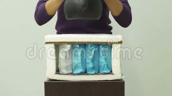 女人把沉重的重量放在一个矫形泡沫床垫与弹簧慢动作视频的预览图