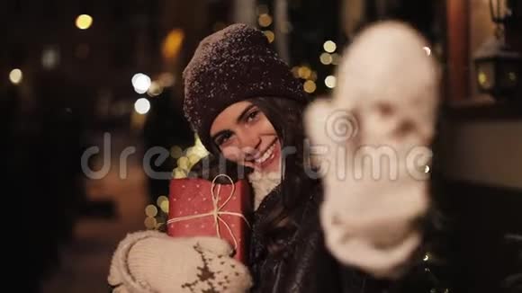 特写微笑少女的肖像看着幸福手捧礼盒站在落雪的户外视频的预览图