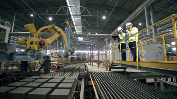 一家现代工厂的工人在测试新的工业机器人设备视频的预览图