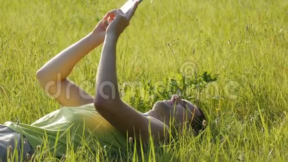 年轻人在夏天躺在草地上在智能手机上打字视频的预览图