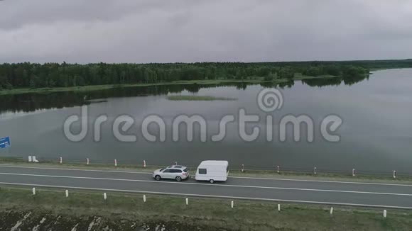 一辆有露营拖车的汽车沿着加拿大一条河的大坝行驶医生视频的预览图