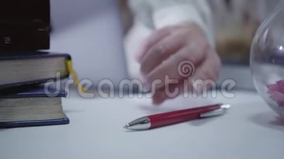 成熟女性白种人的特写手拿红笔躺在桌子上白种人模糊的女人在电脑上视频的预览图