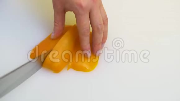 白种人女厨师用刀子切一根黄色的甜椒视频的预览图