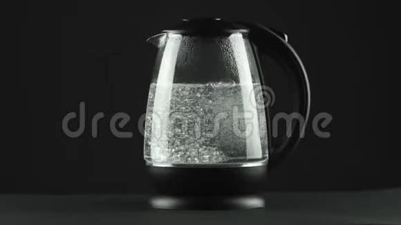 在有透明玻璃墙的电热水壶里水沸腾了黑色背景视频的预览图