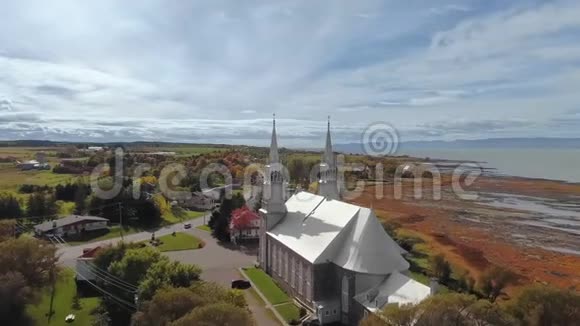 在晴朗的秋日鸟瞰白色教堂和沿海城镇视频的预览图