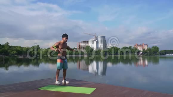 湖边码头肌肉发达的家伙用扩张器伸展手臂视频的预览图